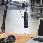 USB condenser microphone mounted on boom arm with cables, desk setup