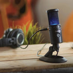 USB condenser microphone on desk stand with blue-lit grille, recording setup