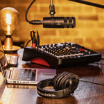 Dynamic podcast microphone with metal body and cable near studio headphones