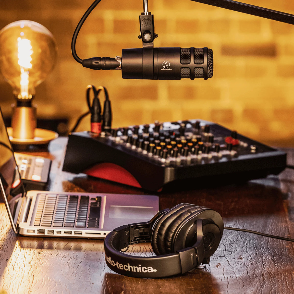 Dynamic podcast microphone with metal body and cable near studio headphones