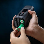 Portable fog machine with green trigger buttons and black housing held in hands